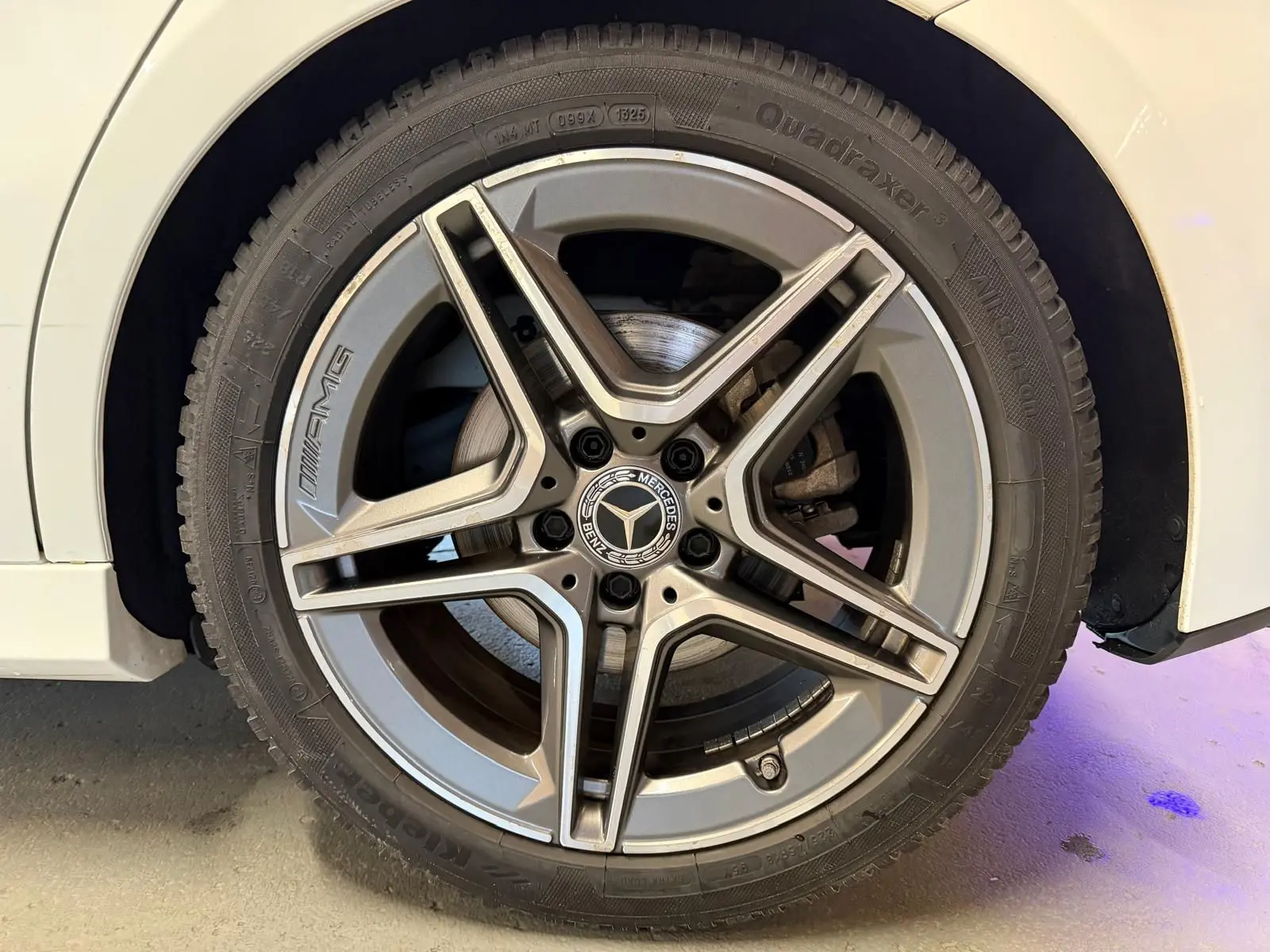 Gros plan sur la jante AMG argentée d’une Mercedes Classe A 220D blanche, vue côté gauche.