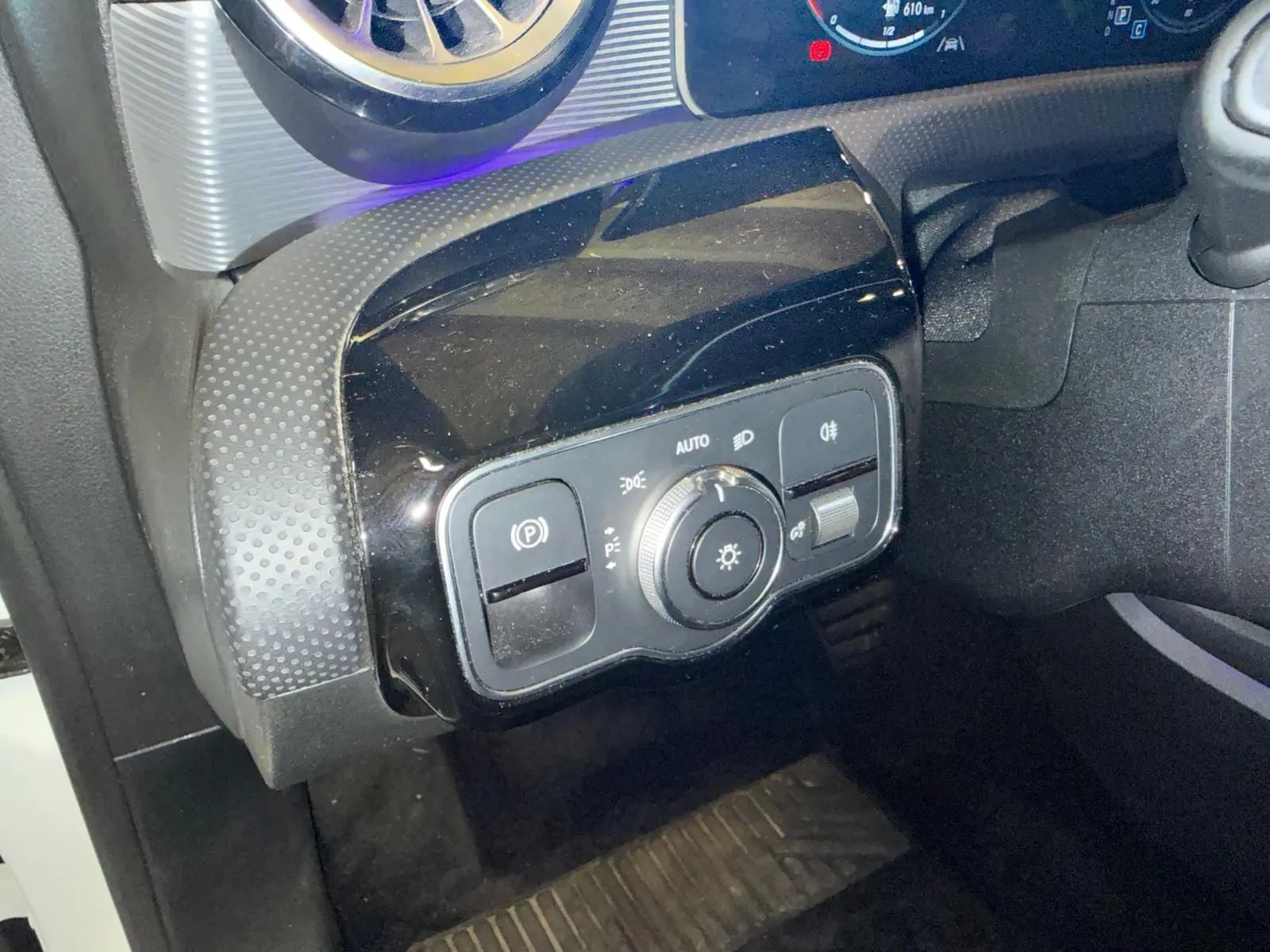 Gros plan sur le tableau de bord côté gauche de la Mercedes Classe A 220D AMG Line 2019 avec commandes d’éclairage et frein à main électrique.