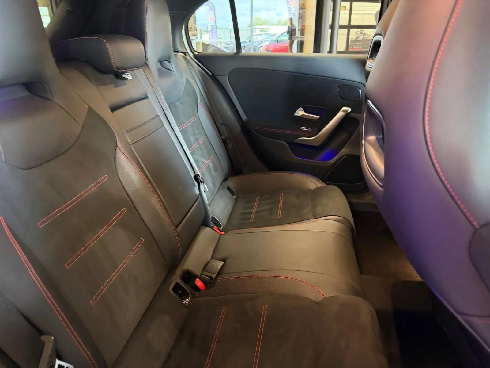 Vue intérieure côté droit des sièges arrière noirs avec surpiqûres rouges d'une Mercedes Classe A 220D AMG Line 2019.