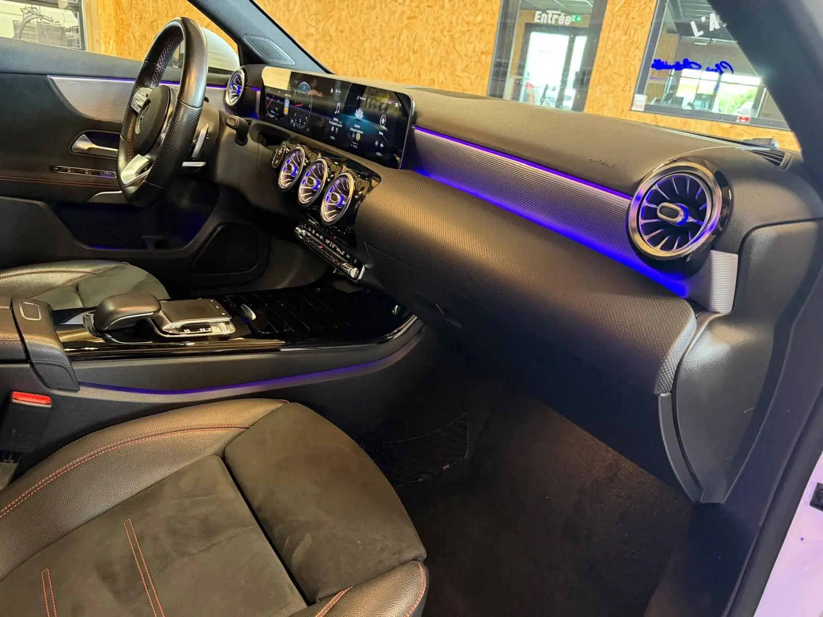 Vue intérieure côté passager de la Mercedes Classe A 220D AMG Line 2019 avec éclairage d'ambiance violet et sellerie noire.