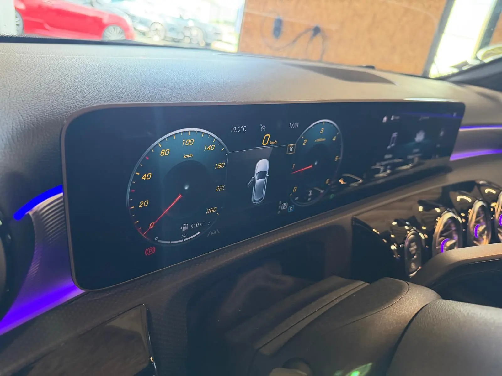Tableau de bord numérique de Mercedes Classe A 220D AMG Line 2019, affichage clair avec éclairage d’ambiance violet.
