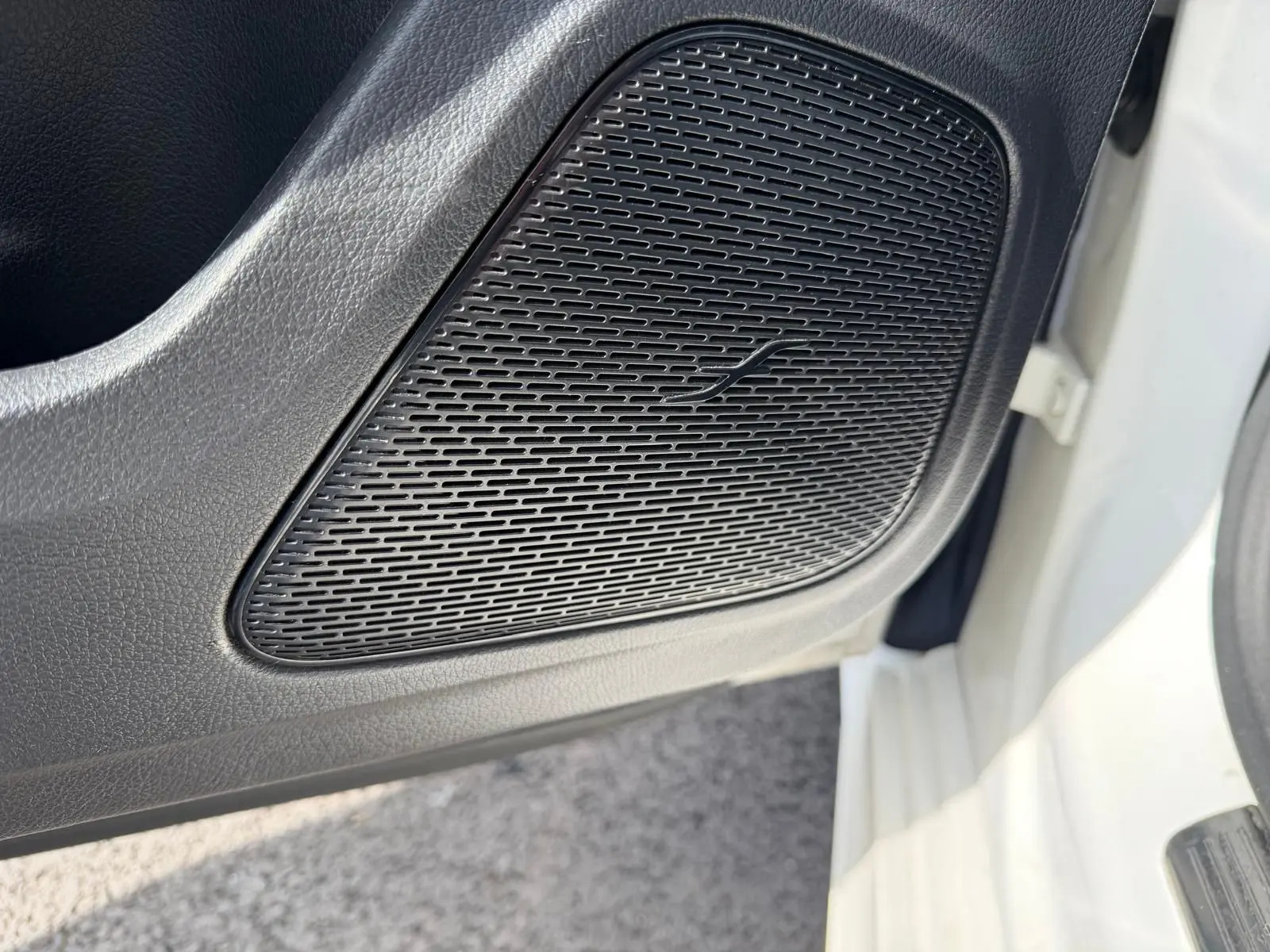 Gros plan sur le haut-parleur noir intégré à la porte avant gauche d'une Mercedes Classe A 220D AMG Line blanche.