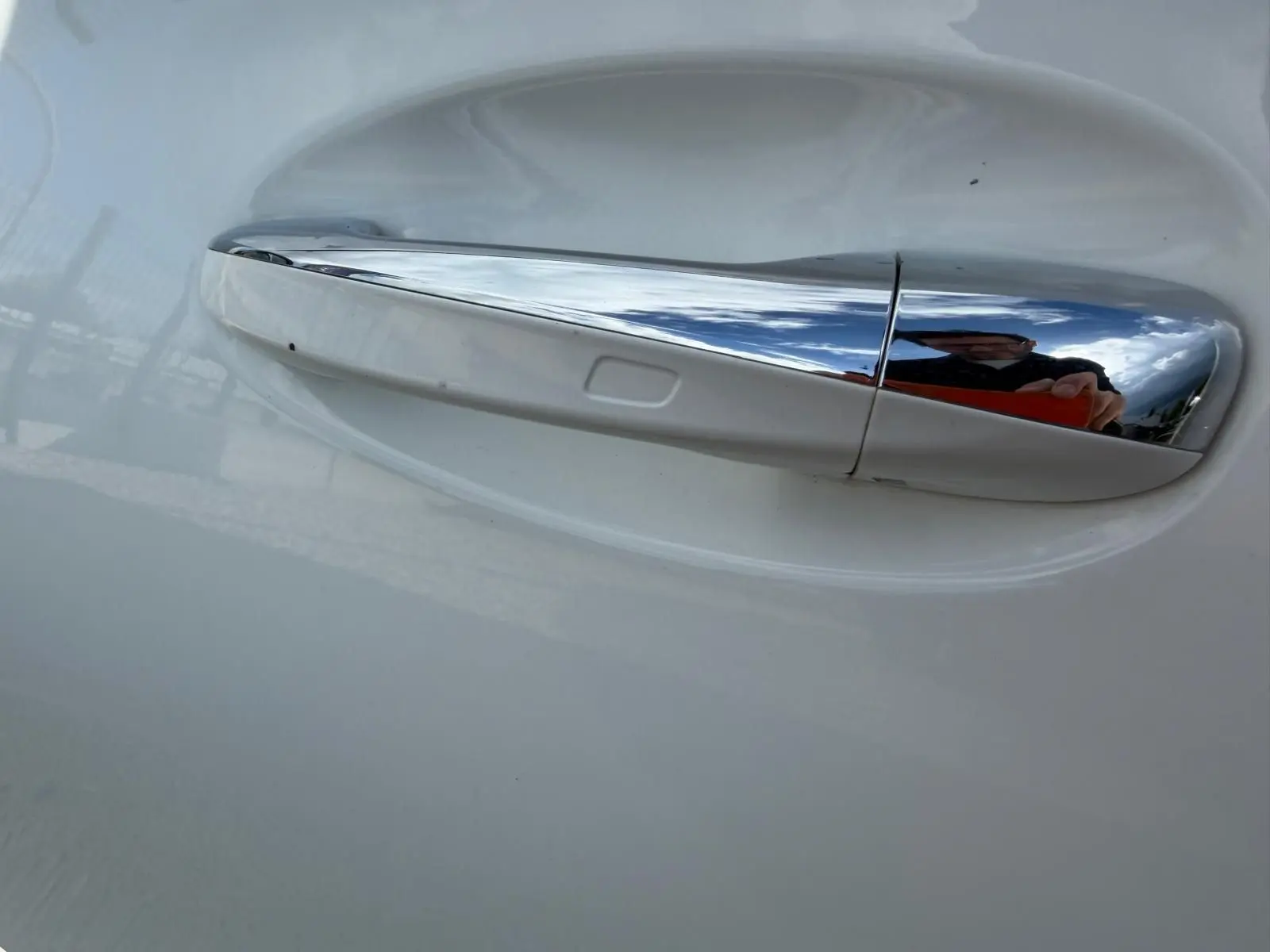Gros plan sur la poignée de porte chromée côté droit d’une Mercedes Classe A 220D AMG Line blanche.