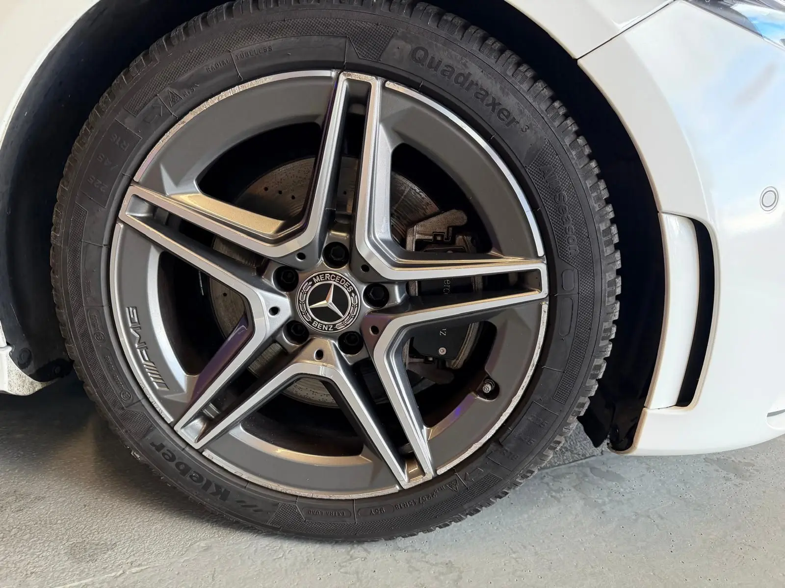 Gros plan sur la roue avant droite blanche d’une Mercedes Classe A 220D AMG Line avec jante AMG cinq branches.