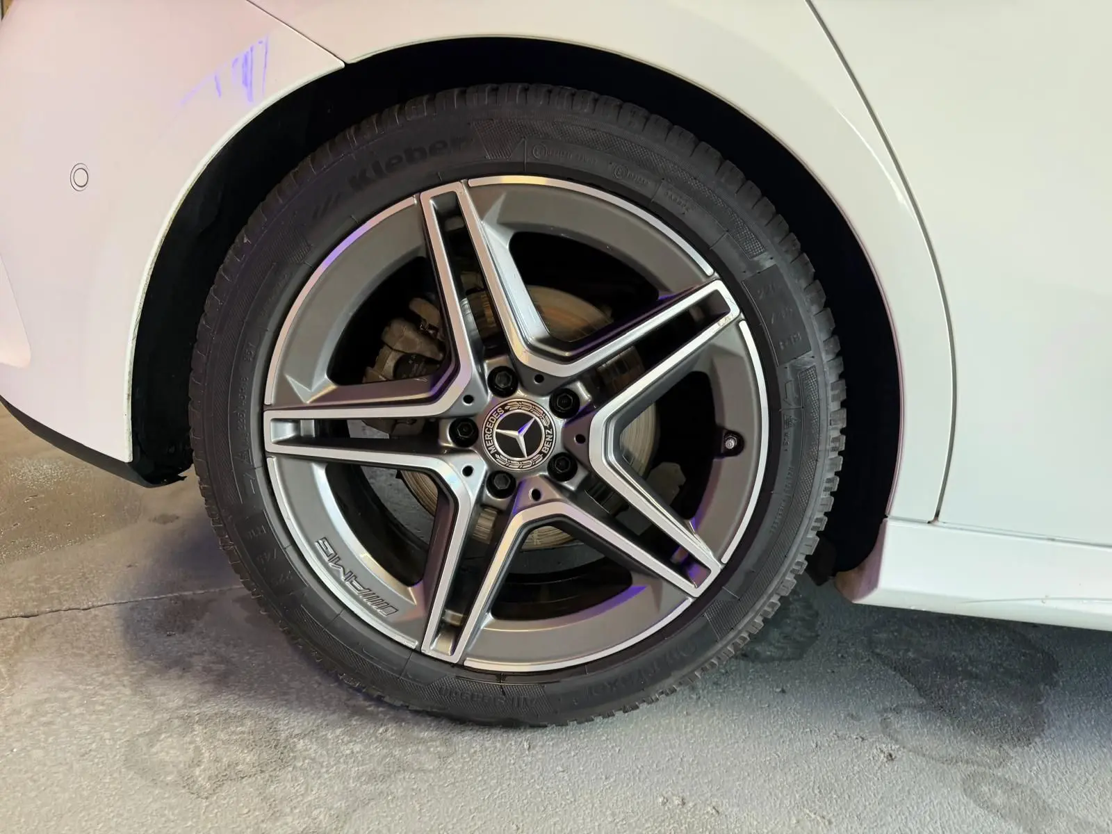 Gros plan sur la roue arrière droite d’une Mercedes Classe A 220D AMG Line blanche, avec jante alliage cinq branches.