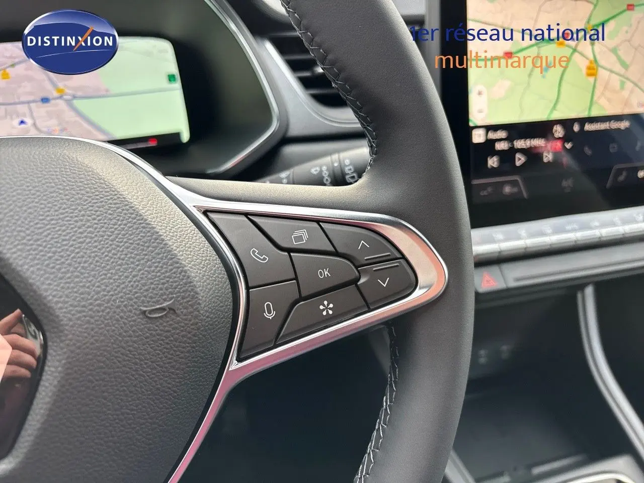Gros plan sur le volant côté droit du Renault Captur II hybride 2025, avec commandes intégrées et écran tactile en arrière-plan.