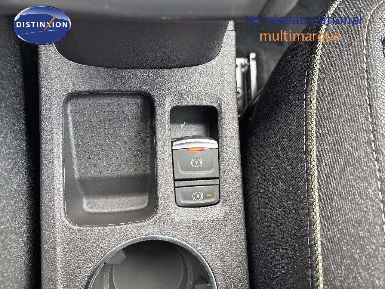 Gros plan sur la console centrale noire du Renault Captur II hybride, montrant les boutons de frein à main et auto hold.