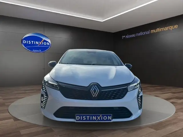 Vue frontale d'une Renault Clio V blanche 2025 avec calandre noire et feux LED Pure Vision dans un showroom.
