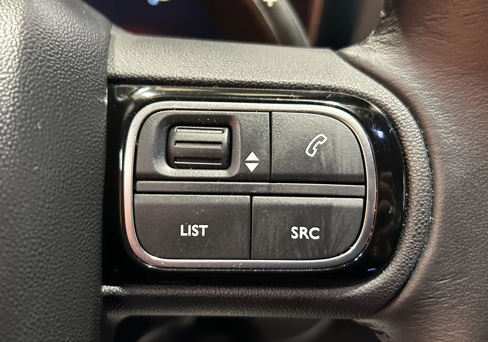 Gros plan sur les commandes noires du volant du Citroën C5 Aircross Ph.2 Hybride 2024, boutons LIST, SRC et téléphone.
