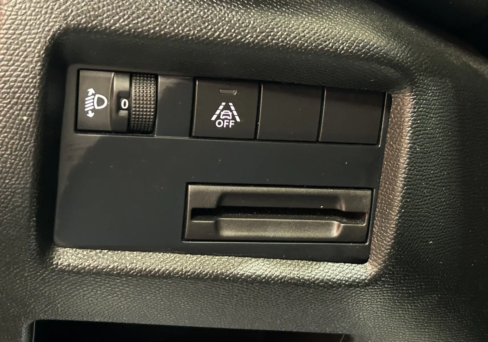 Gros plan sur les commandes intérieures noires du Citroën C5 Aircross 2024, avec réglage phare et assistance de maintien de voie désactivée.