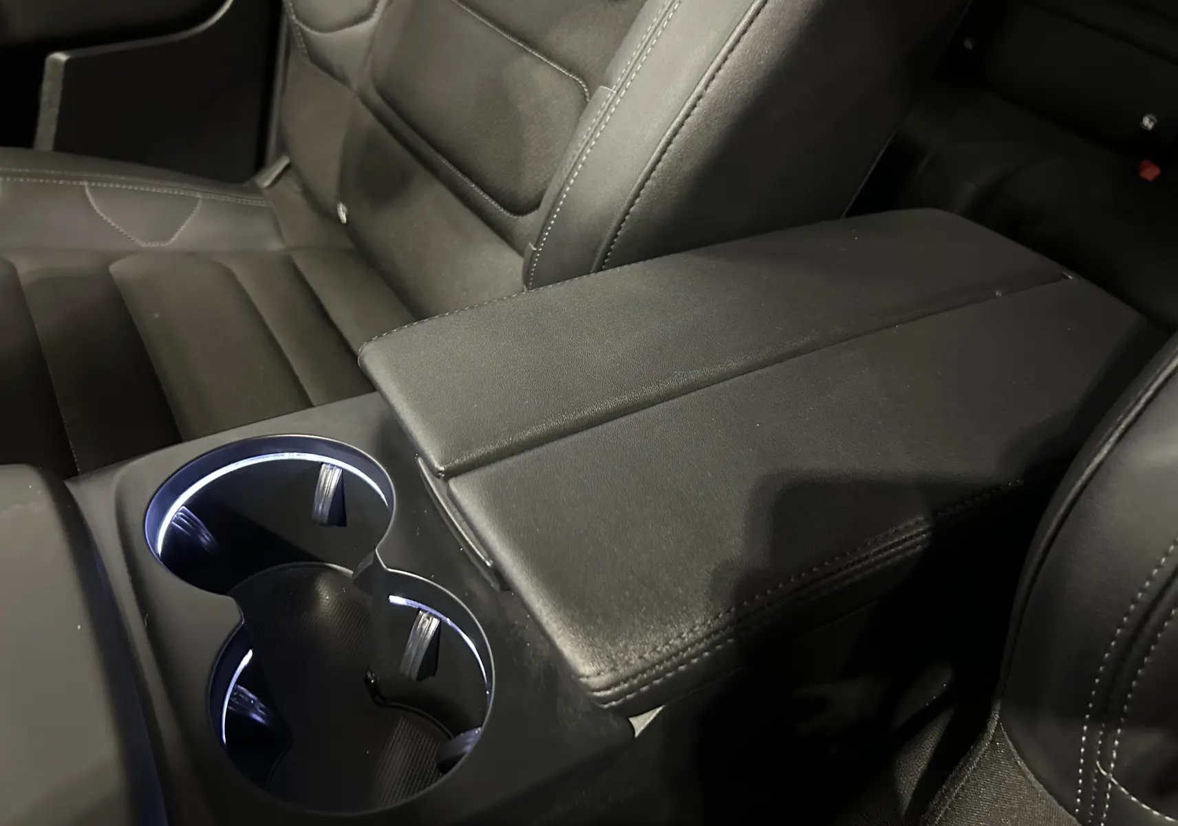 Gros plan sur l'accoudoir central noir et les porte-gobelets éclairés à LED de l'intérieur du Citroën C5 Aircross 2024.