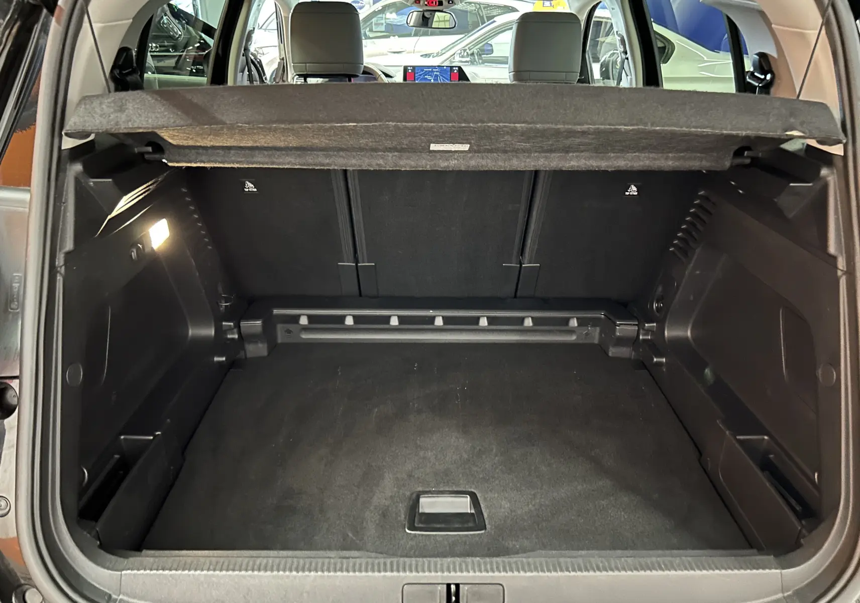 Coffre ouvert vu de l'arrière du Citroën C5 Aircross noir Perla Nera avec banquette arrière et tablette cache-bagages visibles.