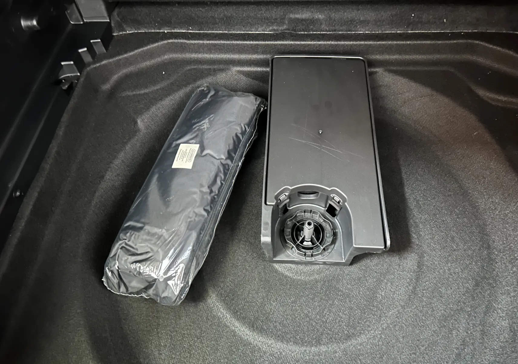 Vue rapprochée du coffre noir d'une Citroën C5 Aircross 2024 avec un kit de secours et un boîtier plastique.