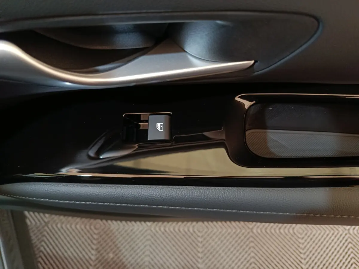 Gros plan sur la commande de lève-vitre électrique côté porte intérieure d’un Hyundai Tucson gris foncé.