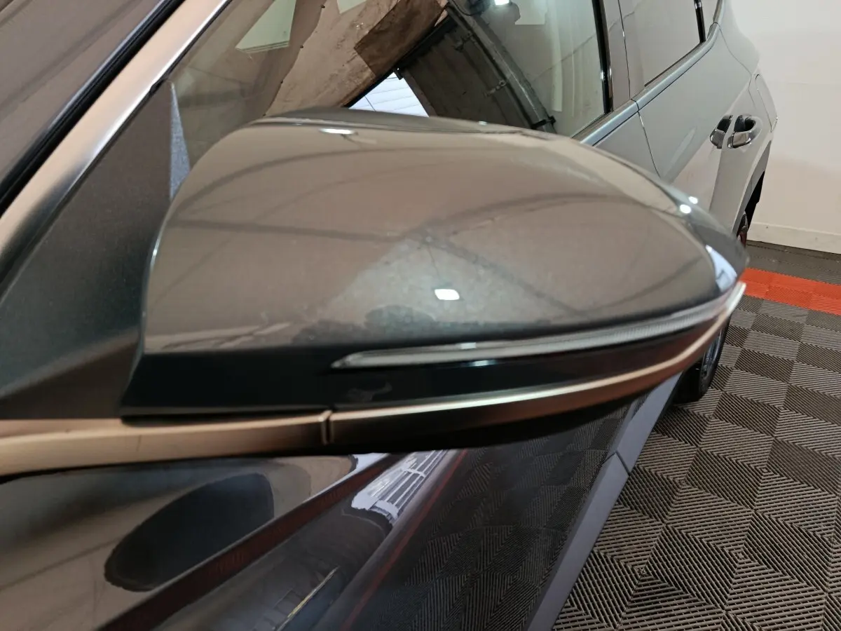 Rétroviseur droit gris foncé du Hyundai Tucson 2025, vue rapprochée avec partie latérale et porte arrière visible.