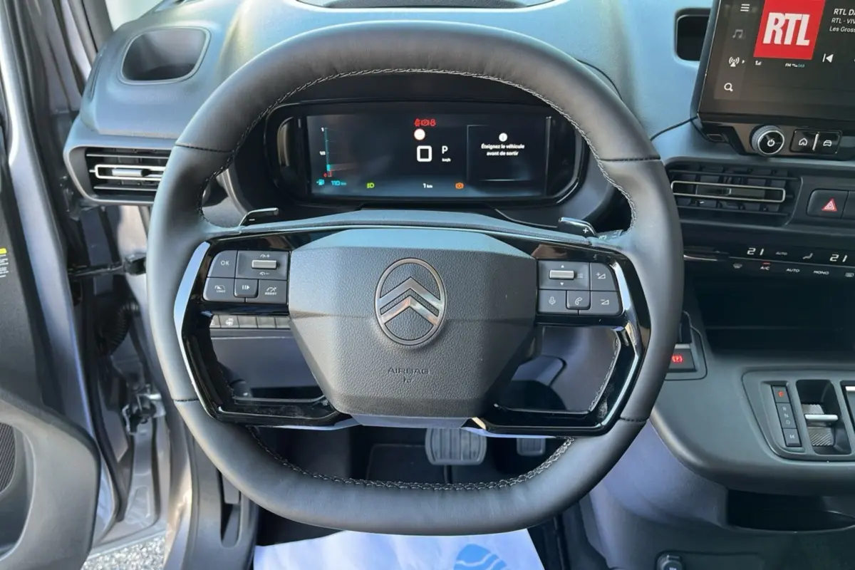 Vue intérieure centrée sur le volant cuir multifonctions du Citroën Berlingo gris Artense avec tableau de bord numérique.