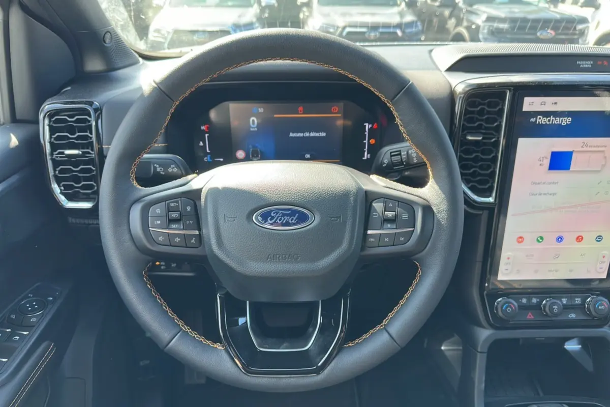 Vue rapprochée du volant cuir noir avec surpiqûres marron du Ford Ranger 2026, tableau de bord et écran tactile visibles.