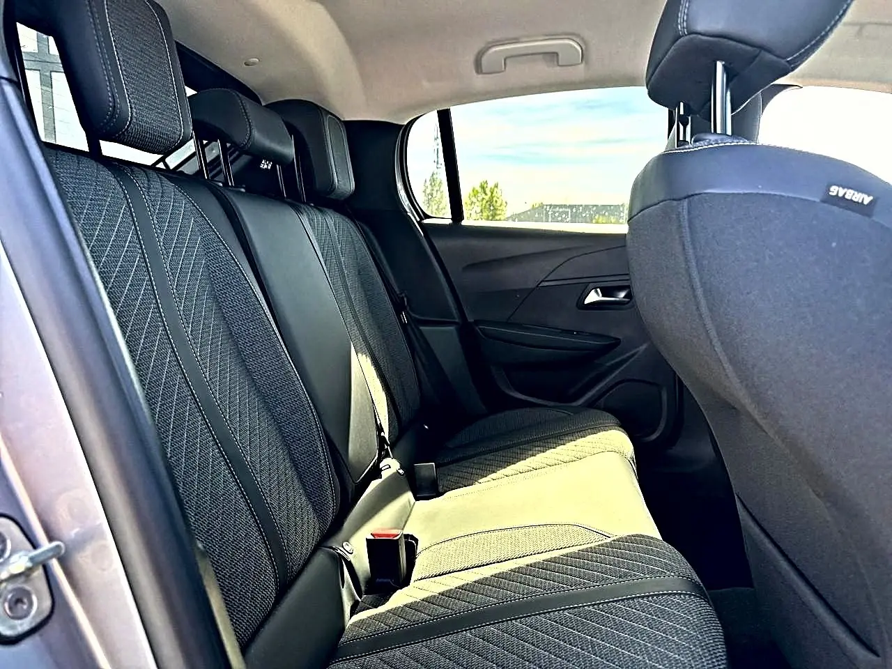 Vue intérieure côté gauche des sièges arrière en tissu gris de la Peugeot 208 1.2 100 Allure 2025.