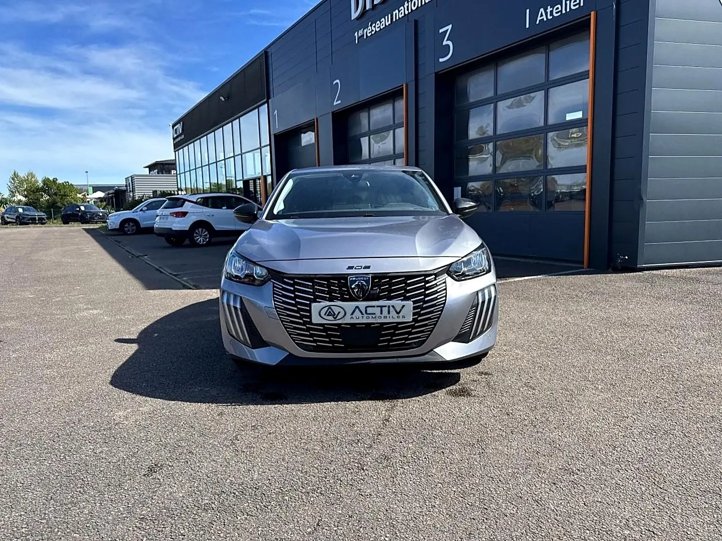 Peugeot 208 gris artense vue de face, mettant en valeur sa calandre distinctive et ses phares LED.