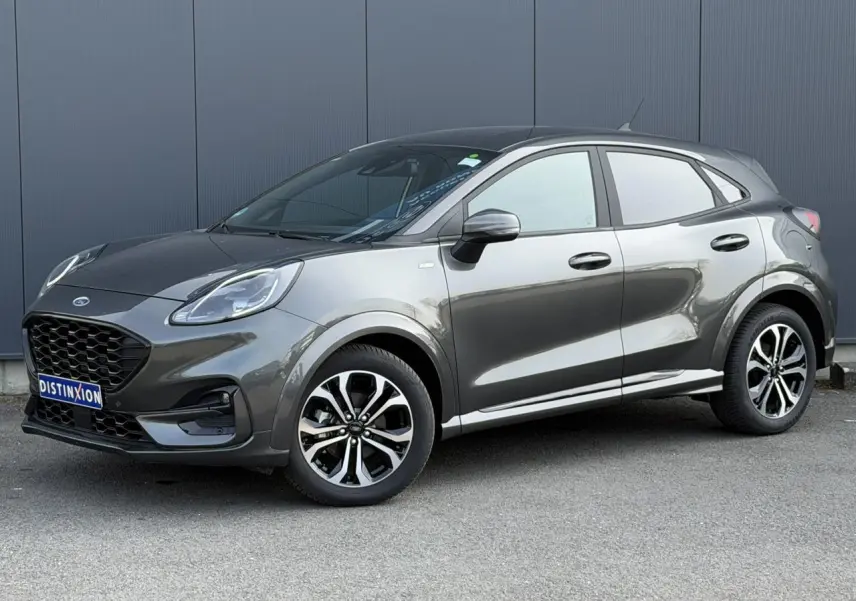 Ford Puma Ecoboost 155 ST Line gris magnétique en 3/4 avant droit, avec jantes alliage et calandre noire distinctive.
