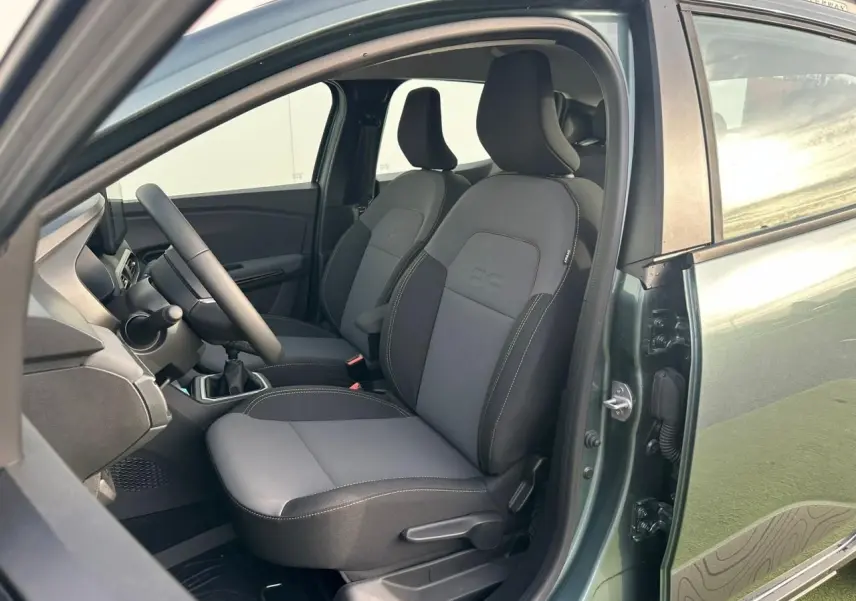 Vue intérieure côté conducteur de la Dacia Sandero III Stepway 2025 vert cèdre, montrant les sièges avant et le volant.
