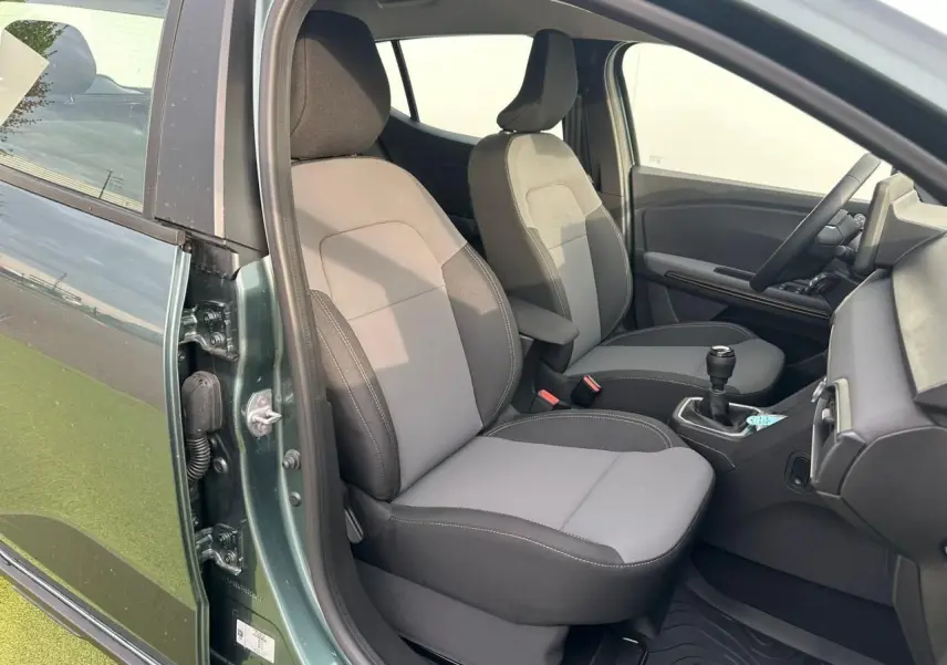 Vue intérieure côté conducteur de la Dacia Sandero III Stepway 2025 vert cèdre, sièges gris et console avec levier manuel.