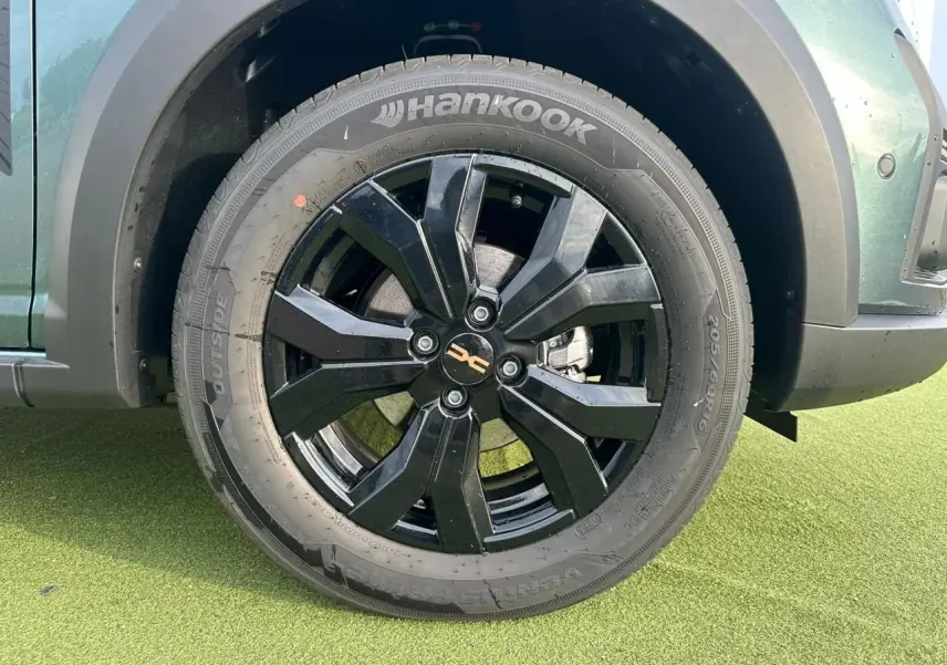 Gros plan sur la roue avant gauche noire brillante d'une Dacia Sandero Stepway 2025 Vert Cèdre avec pneu Hankook.