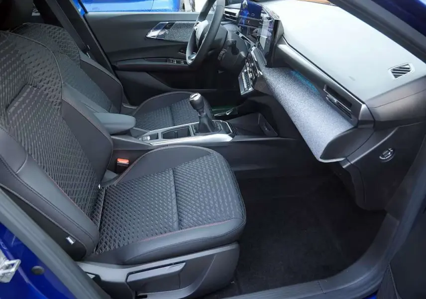 Vue intérieure côté conducteur de la Renault Clio VI 6 TCE 115 Techno Plus bleu iron, avec sièges tissu noir et console centrale moderne.