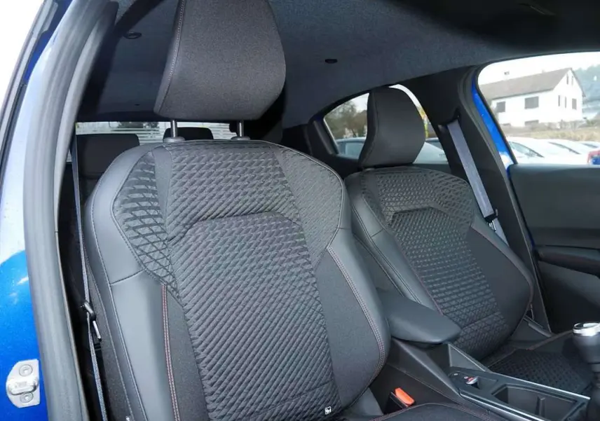 Vue intérieure rapprochée des sièges avant en tissu noir avec surpiqûres rouges d’une Renault Clio bleu iron.