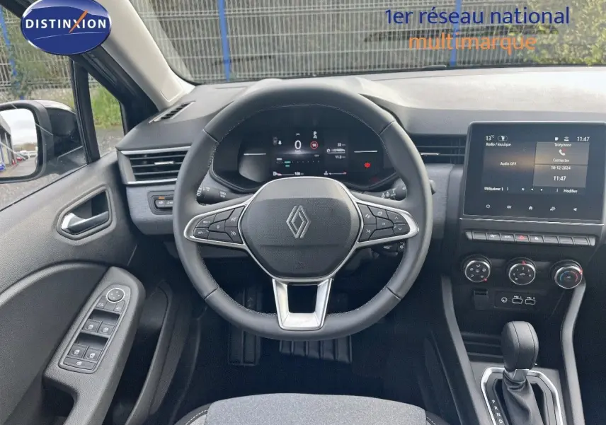 Vue intérieure centrée sur le volant et tableau de bord de la Renault Clio 2024, avec écran tactile et commandes modernes.