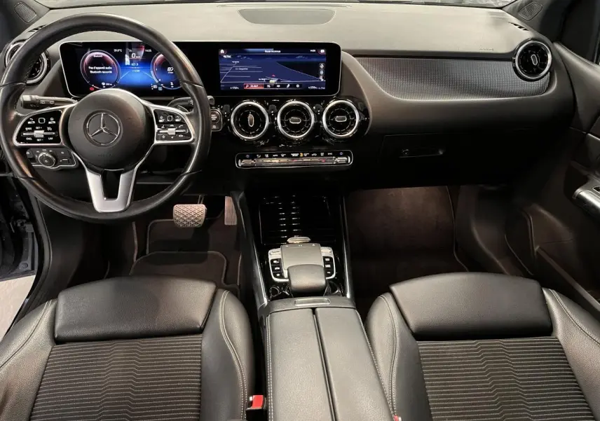 Intérieur noir de la Mercedes Classe B 180 d 2019, vue frontale sur tableau de bord digital et volant multifonction.