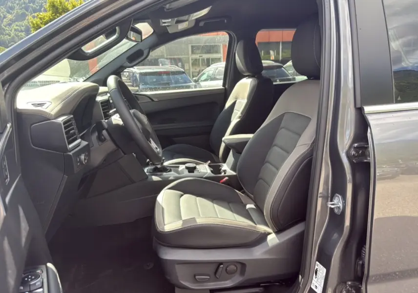 Vue intérieure côté conducteur du Volkswagen Amarok Simple Cabine 2026 gris foncé, sièges cuir et tableau de bord moderne.