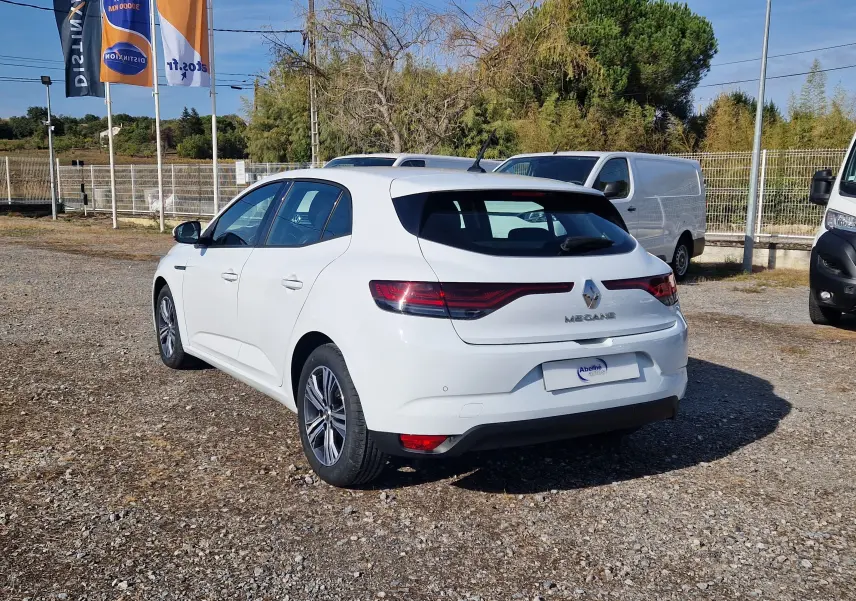 Renault Mégane blanche vue 3/4 arrière droit sur parking, avec feux arrière LED et jantes alliage 16 pouces.