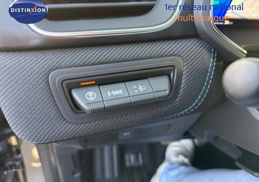 Détail intérieur montrant les boutons de commande E-SAVE et réglage des phares sur Renault Symbioz gris Cassiope, côté conducteur.