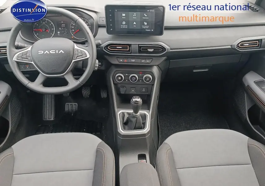 Intérieur de la Dacia Sandero 2025 vue de face, tableau de bord noir avec écran tactile et boîte manuelle.