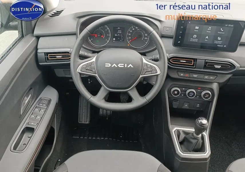 Intérieur de la Dacia Sandero 2025 vue du poste de conduite, volant DACIA, boîte manuelle et écran tactile central.