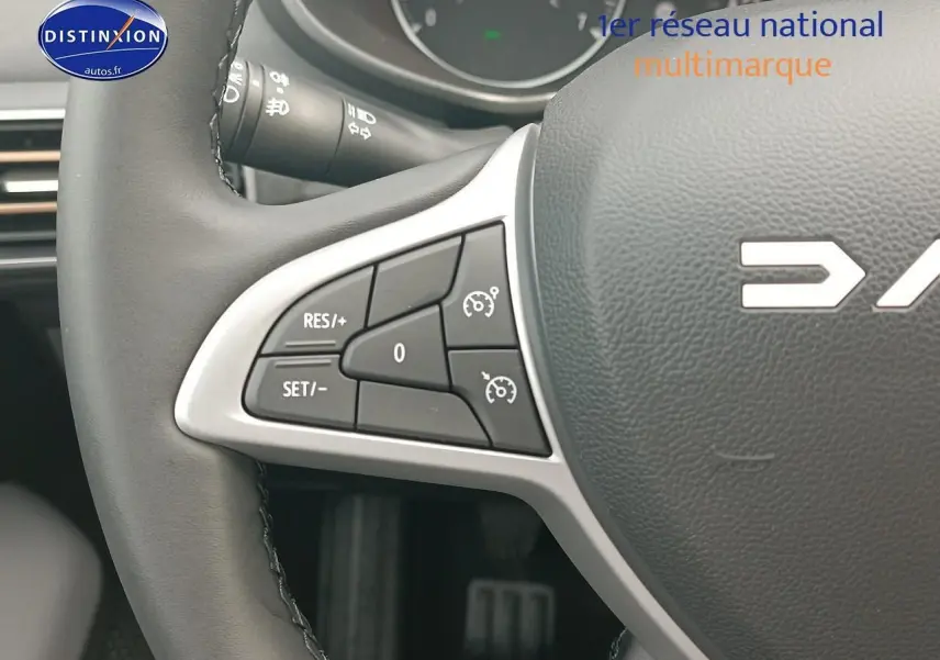 Gros plan sur les commandes de régulateur de vitesse à gauche du volant noir de la Dacia Sandero 2025.
