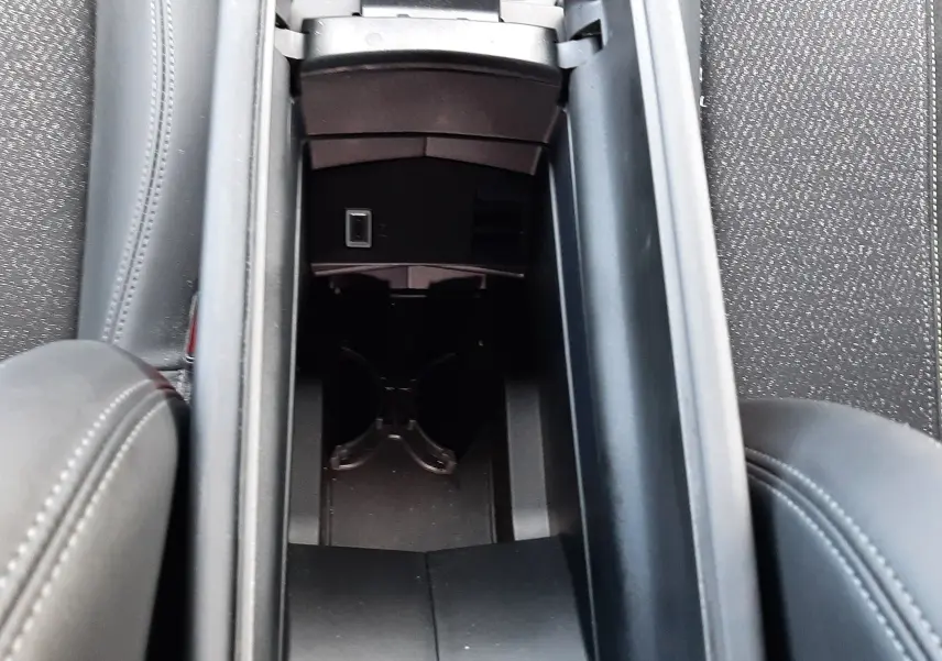 Vue plongeante sur le rangement central noir entre les sièges avant d'une Peugeot 308 SW 2024, finition cuir gris.