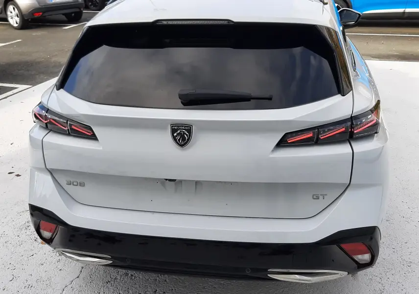 Vue arrière d'une Peugeot 308 SW blanche Okenite avec feux LED distinctifs et badge GT visible.