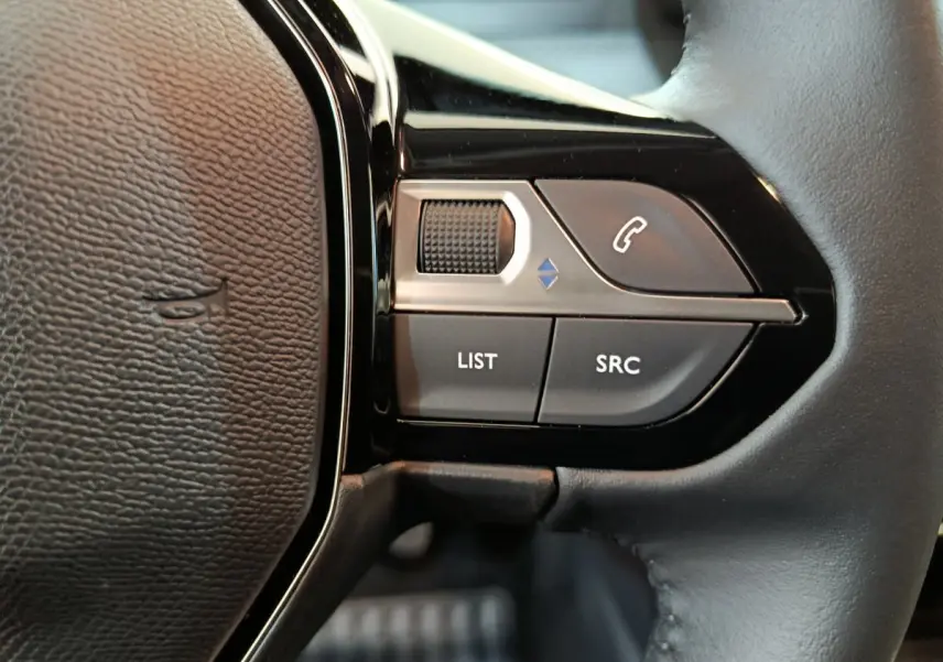 Gros plan sur les commandes gauche du volant cuir noir de la Peugeot 208 PureTech 100 S&S Allure 2025.