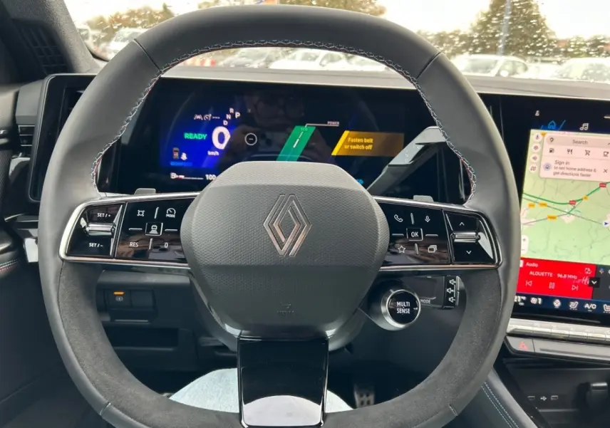 Vue intérieure centrée sur le volant en suède noir du Renault Rafale esprit Alpine avec tableau de bord numérique et écran tactile.