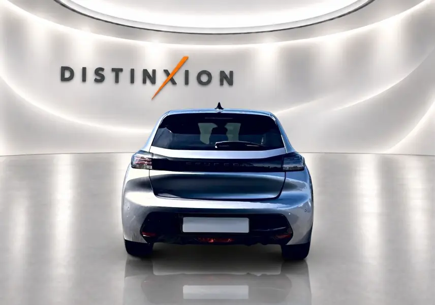 Vue arrière d'une Peugeot 208 1.2 100 Allure gris Artense dans un showroom lumineux avec logo Distinxion en arrière-plan.
