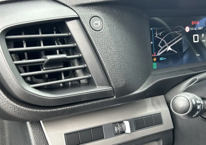 Détail de la console centrale et tableau de bord numérique du Citroën Jumpy Fourgon gris acier, avec écran GPS et commandes.