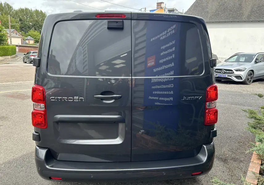 Vue arrière d'un Citroën Jumpy Fourgon gris acier 2025 avec portes battantes et feux rouges bien visibles.