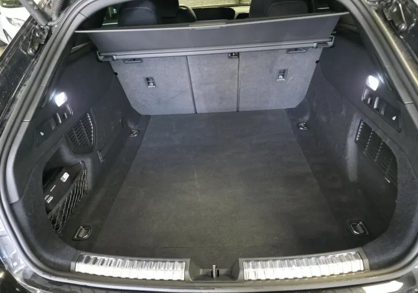 Coffre ouvert vu de l'arrière d'un break Audi A5 noir, avec tapis et éclairage intérieur LED.