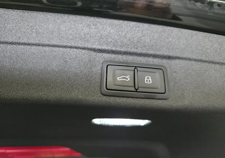 Boutons d'ouverture de hayon et de verrouillage intégrés sur le panneau intérieur du coffre d'une Audi A5 Avant noire.