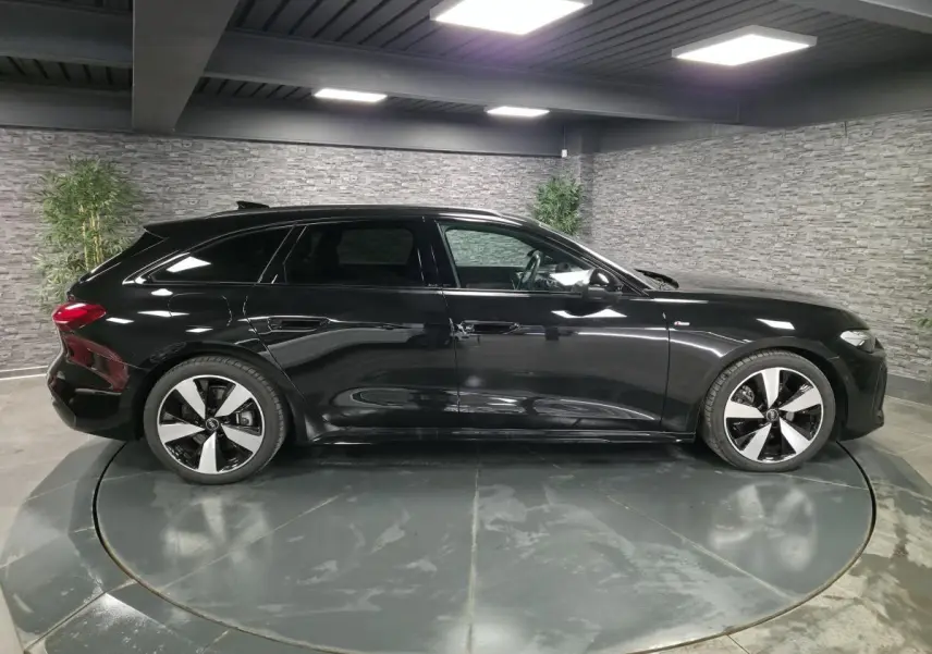 Profil côté gauche d'une Audi A5 Avant S line noire 2025 avec jantes 5 branches doubles et vitres surteintées.