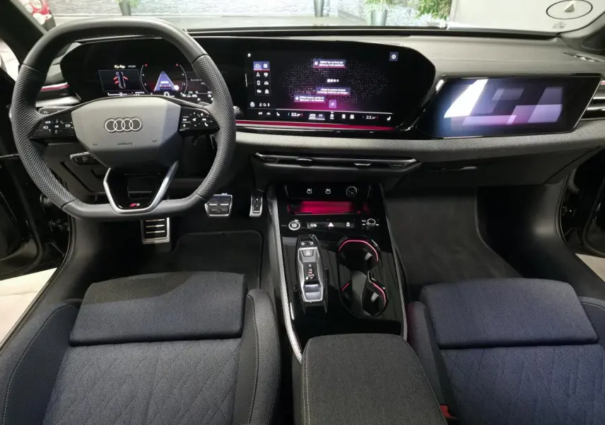 Vue intérieure avant de l'Audi A5 Avant 2025, tableau de bord noir avec écran digital et volant sport multifonction S line.