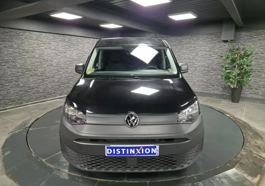 Vue de face d'un Volkswagen Caddy Cargo 2024 noir avec pare-chocs gris et calandre inférieure à motif nid d'abeille.