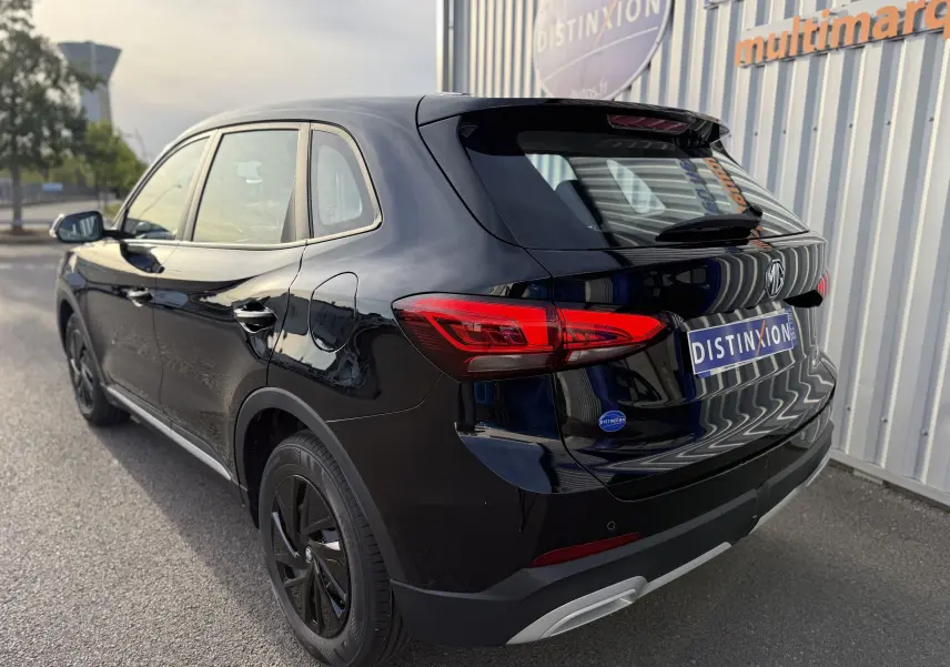 Vue 3/4 arrière droite d’un MG MOTOR ZS Hybrid 197 Standard noir brillant, avec feux arrière LED et jantes noires.